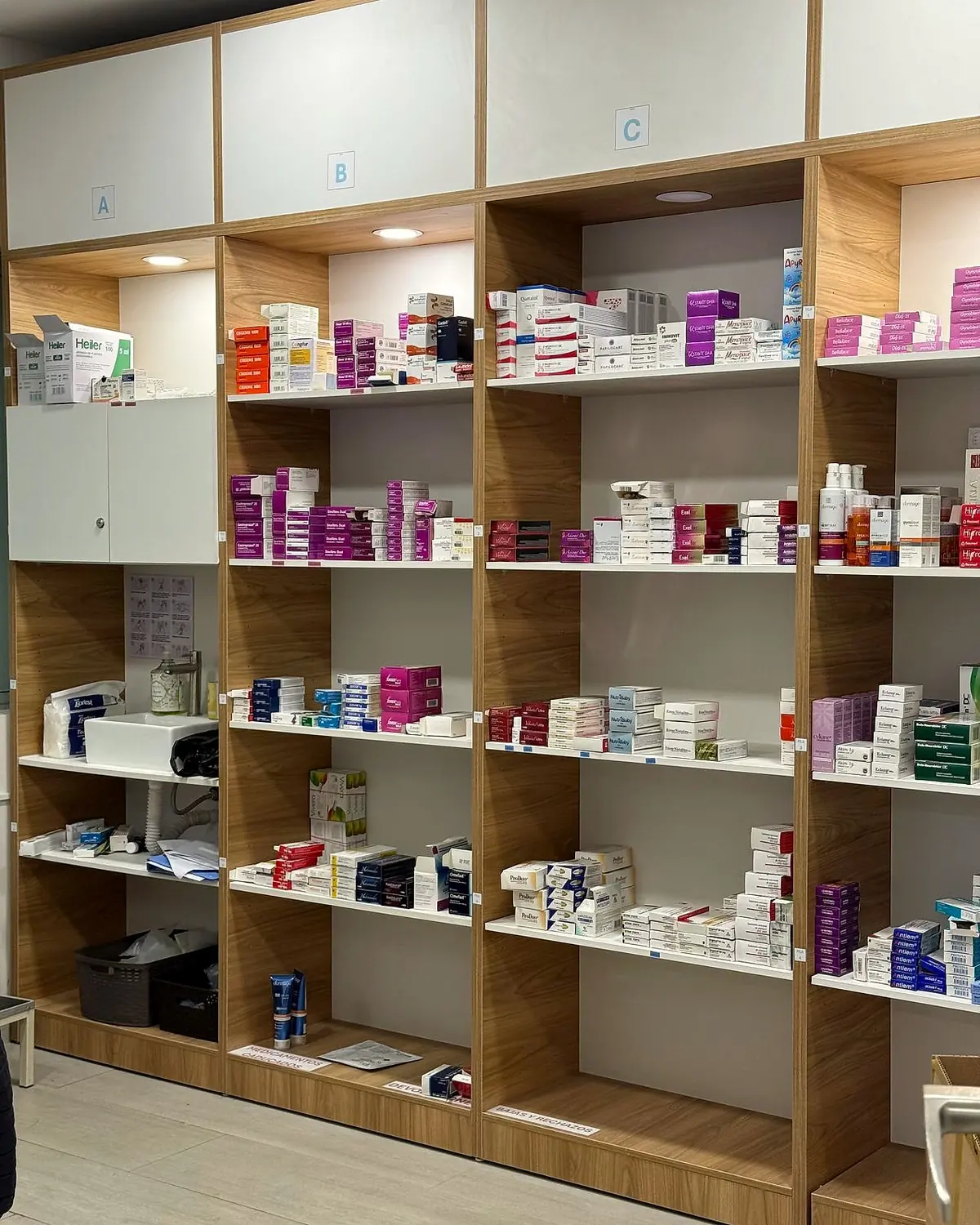 Estantería de madera y blanco de la farmacia, con medicamentos ordenados por secciones