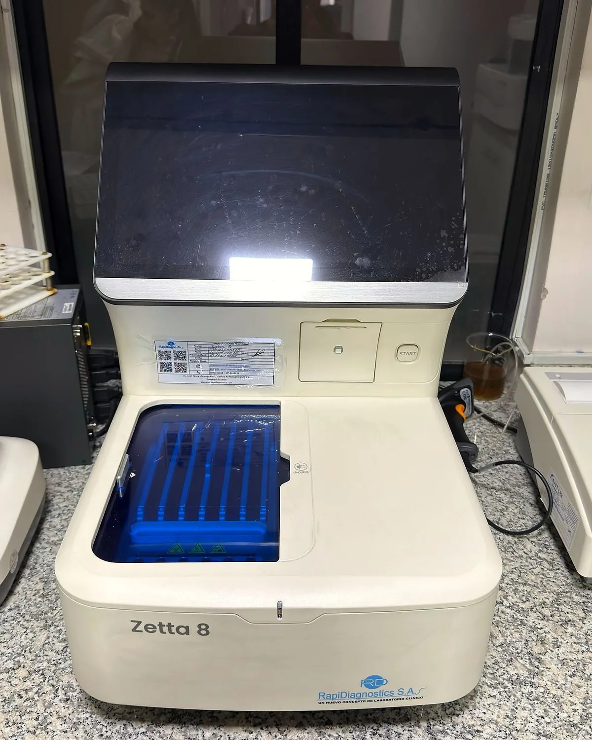 Equipo con gradilla de tubos azules sobre la mesada del laboratorio