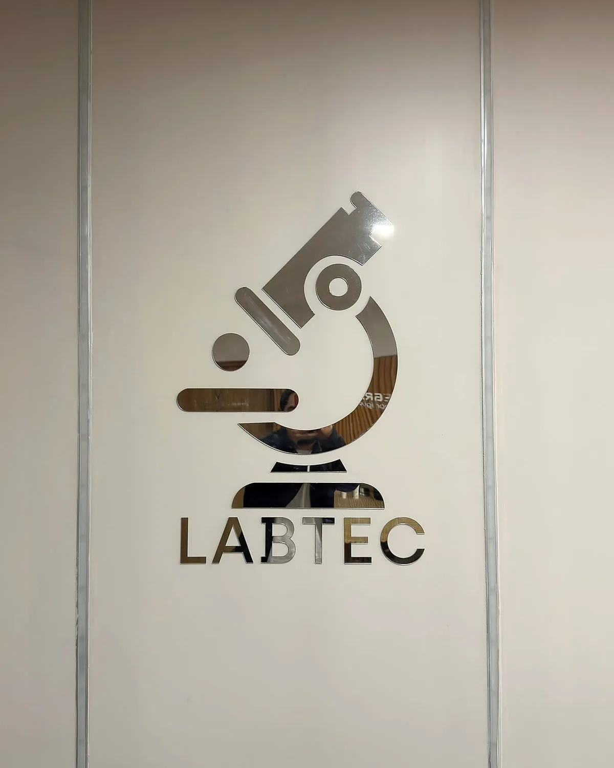 Puerta del laboratorio, con su isotipo de microscopio grabado en el vidrio