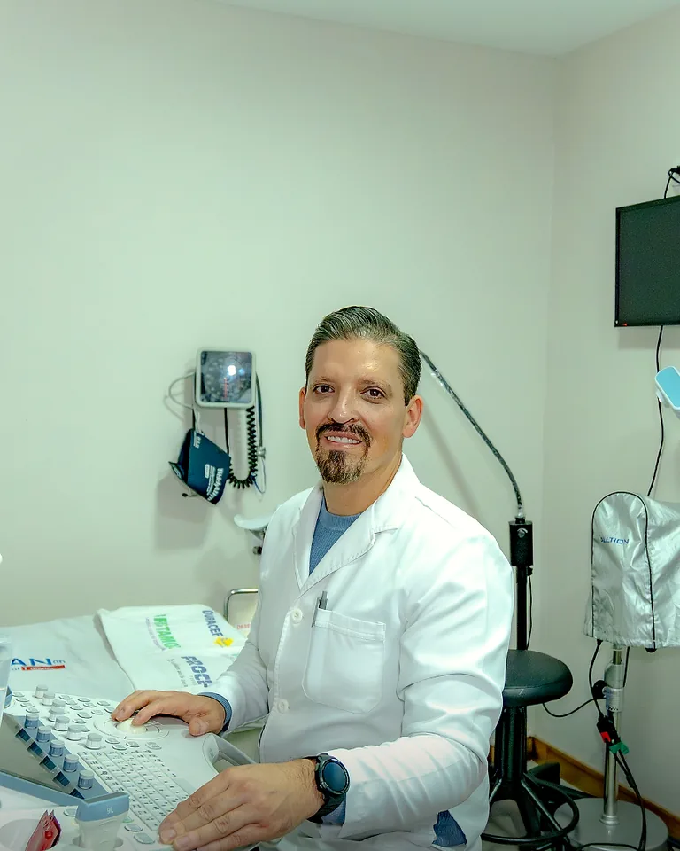 Referencia: El ecógrafo en uso, con las manos del médico sobre el equipo