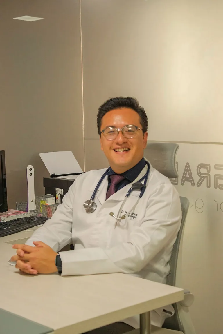 Dr. Pedro Ojeda sonriendo en su escritorio de consulta